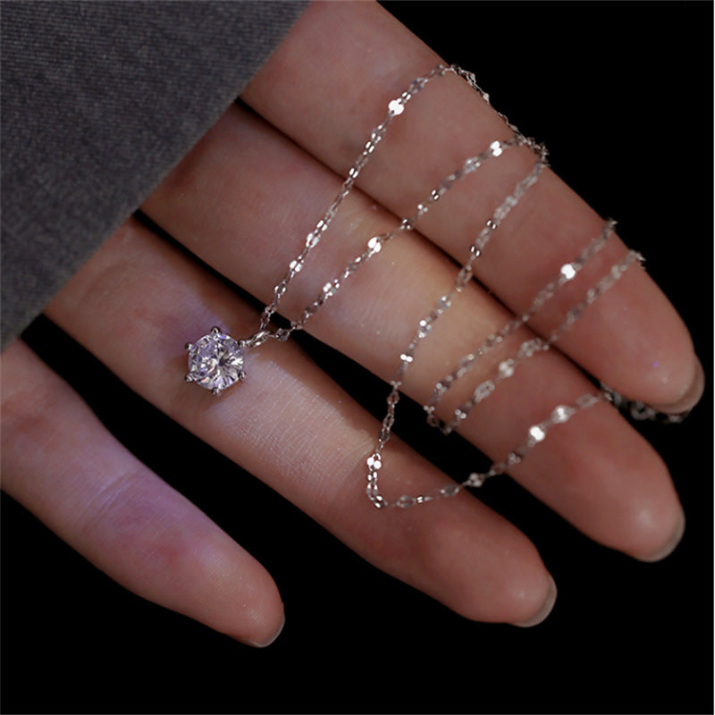 Silver necklace held in hand against dark background