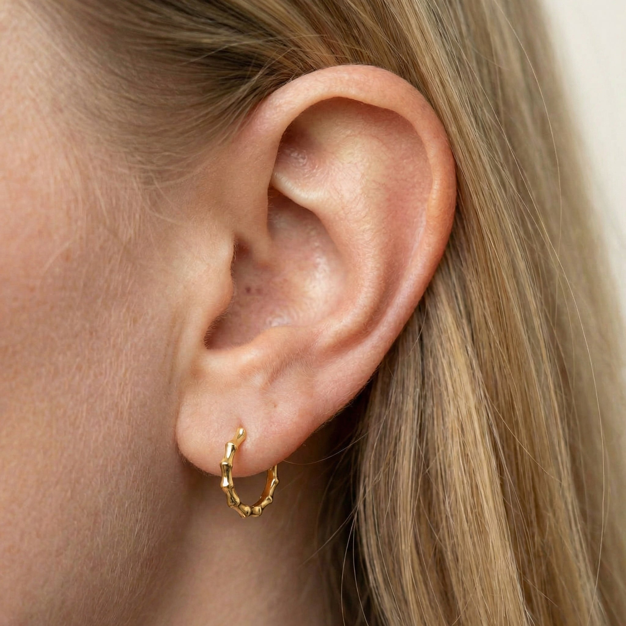 Gold-plated bamboo hoop earring worn on ear with hair down