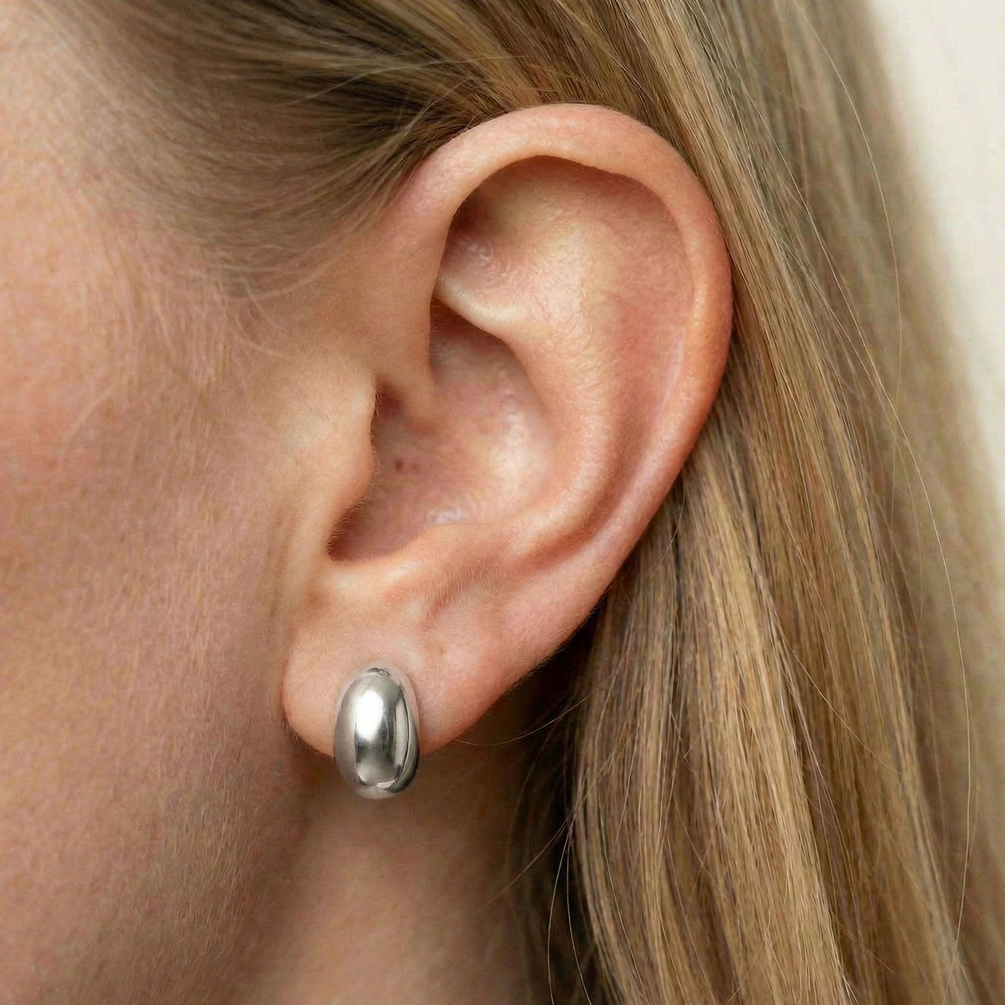 Stud earrings silver earring worn on model's ear, close-up