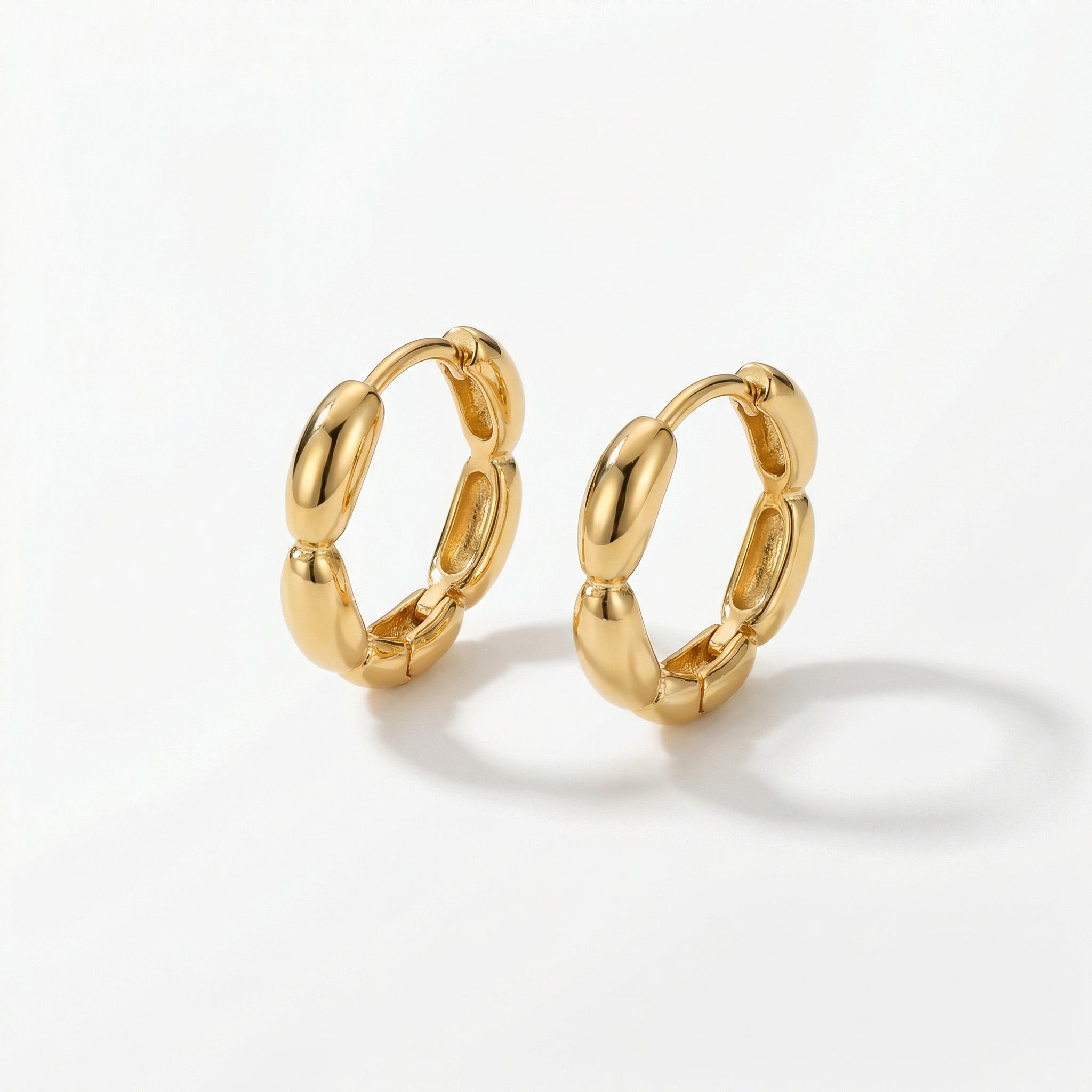Gold-plated huggie hoops on white