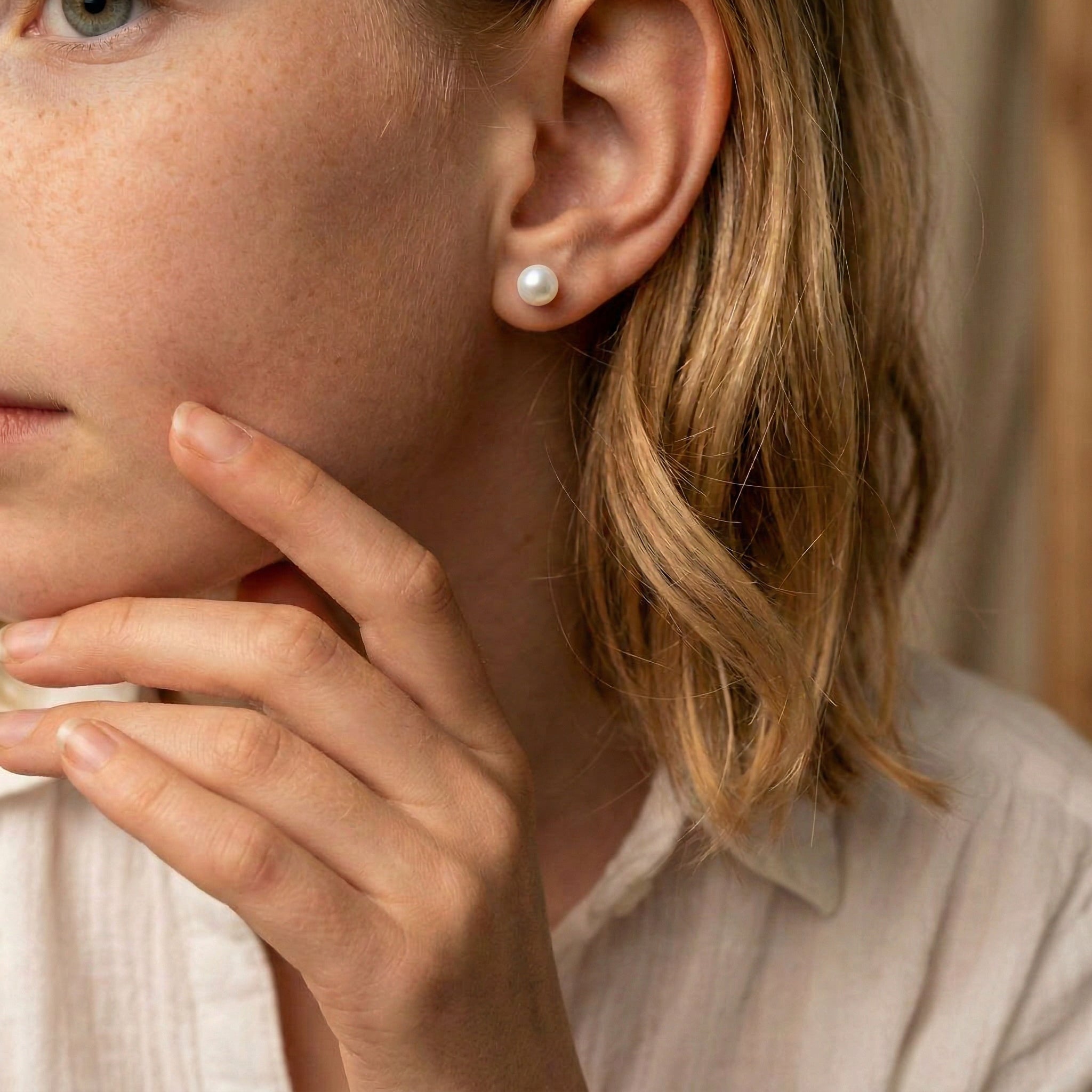Gold-plated pearl earring on model's ear