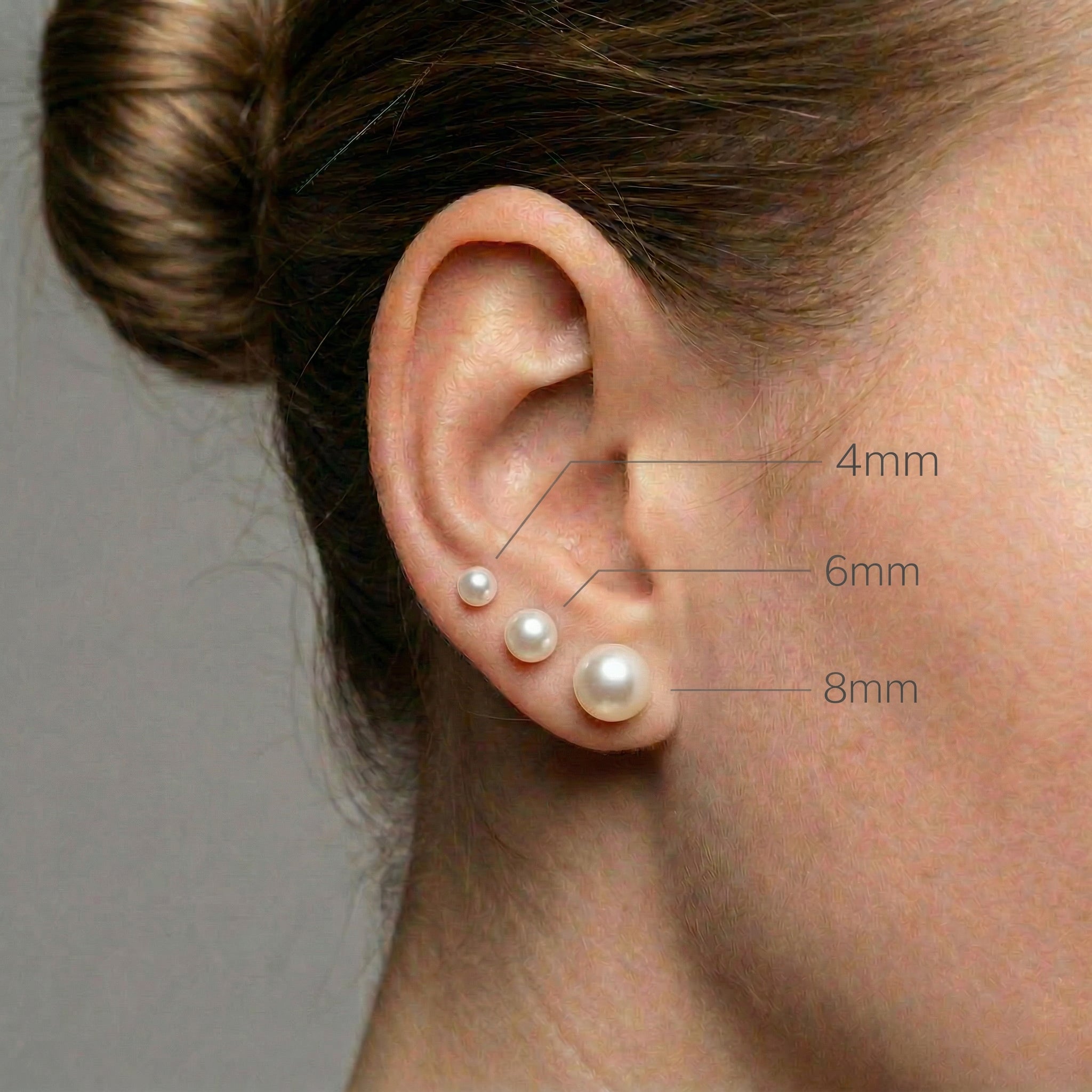 Gold-plated different size pearl studs on ear