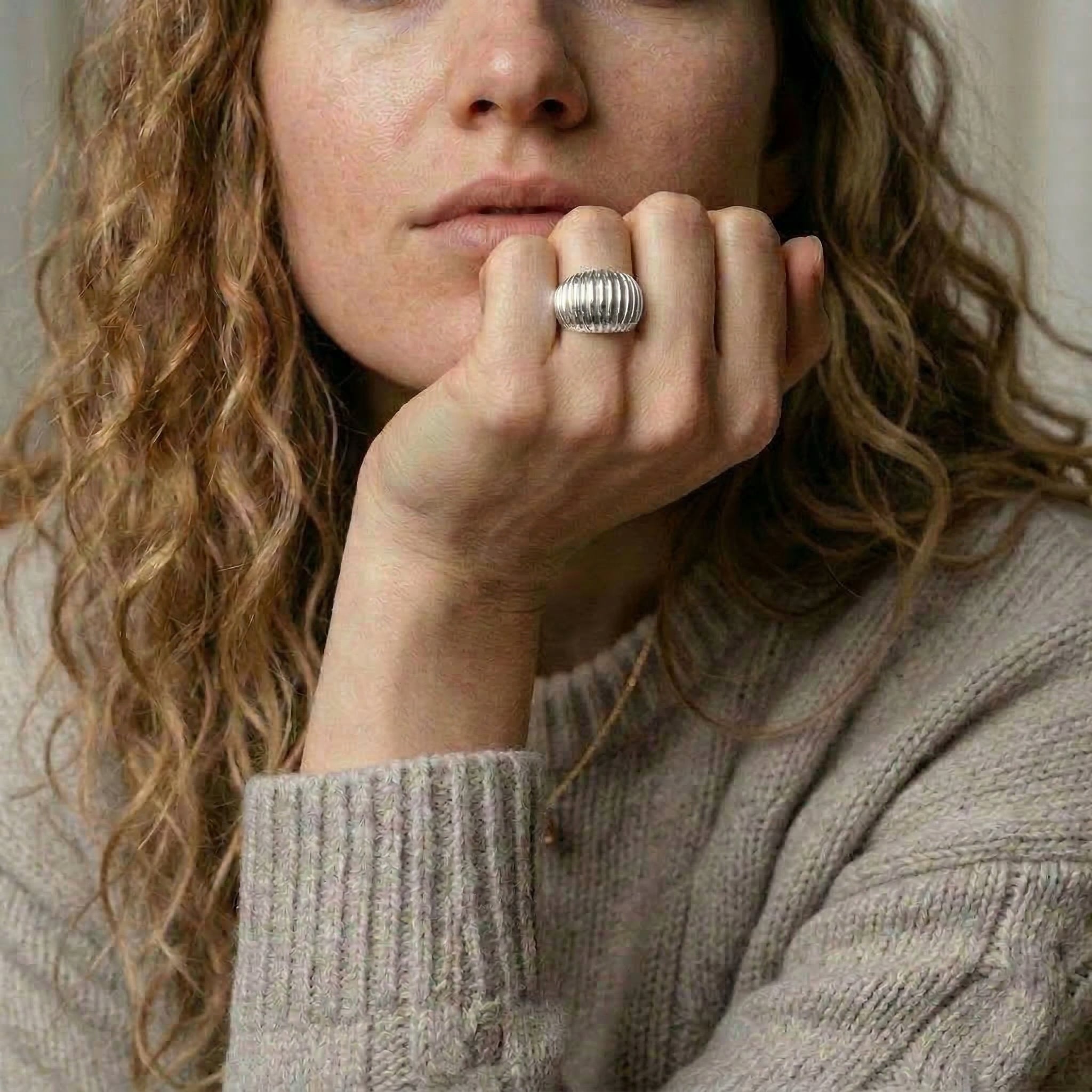 Silver ring worn on hand with sweater