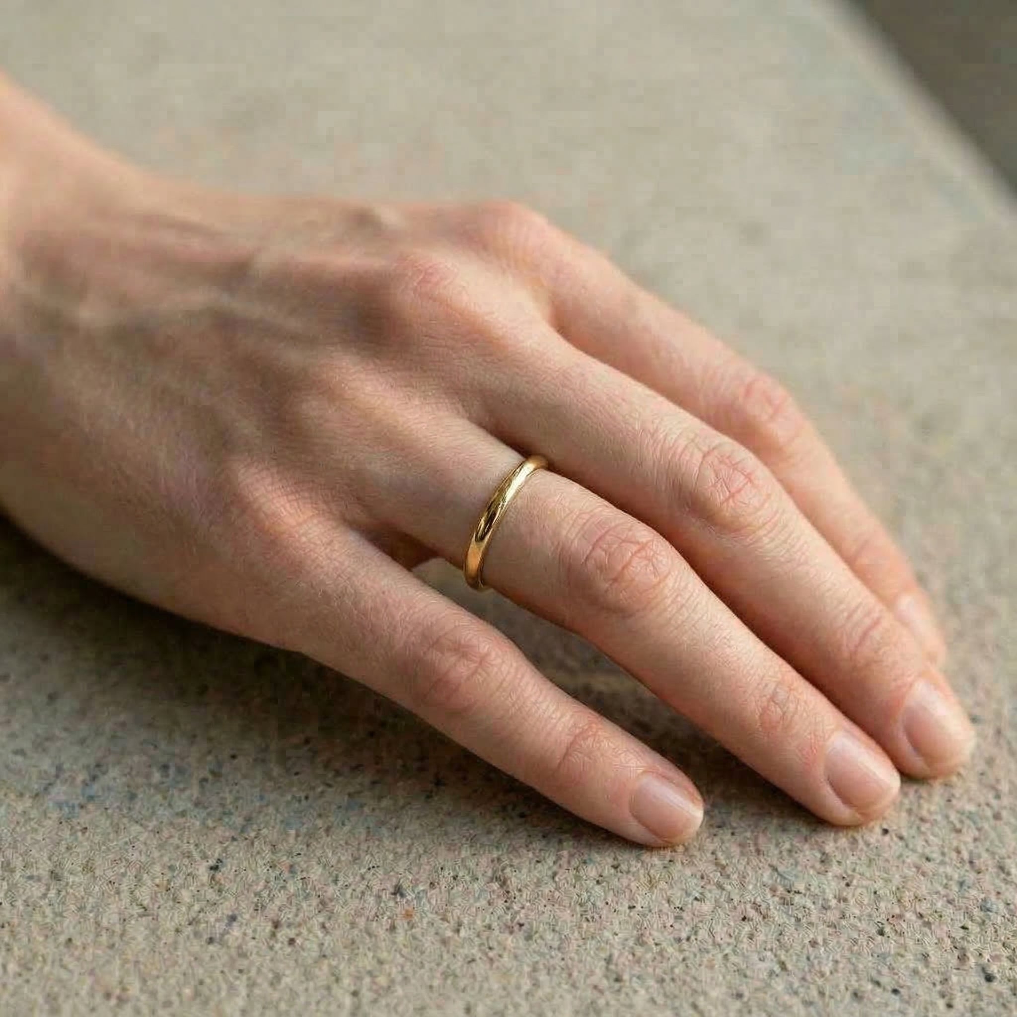 Gold-plated ring on hand, concrete background