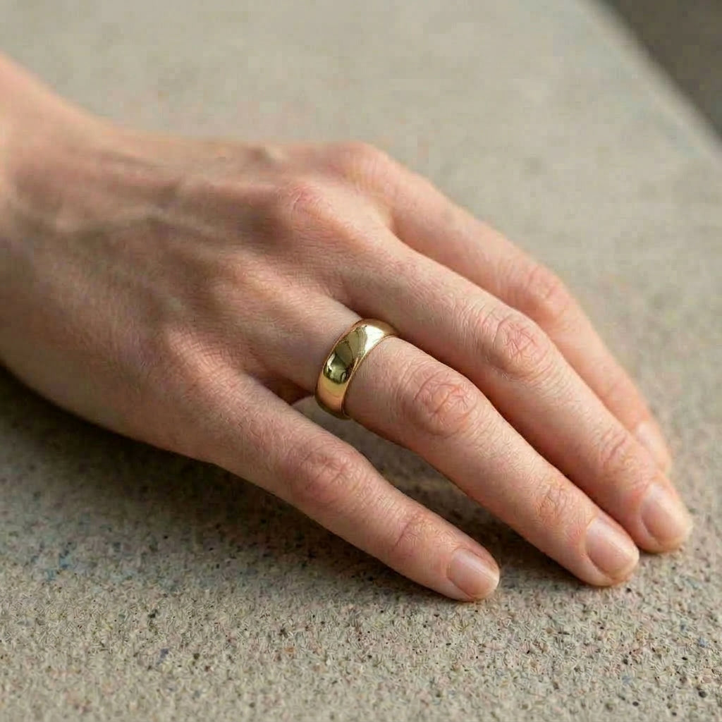 Gold-plated ring worn on hand, concrete background