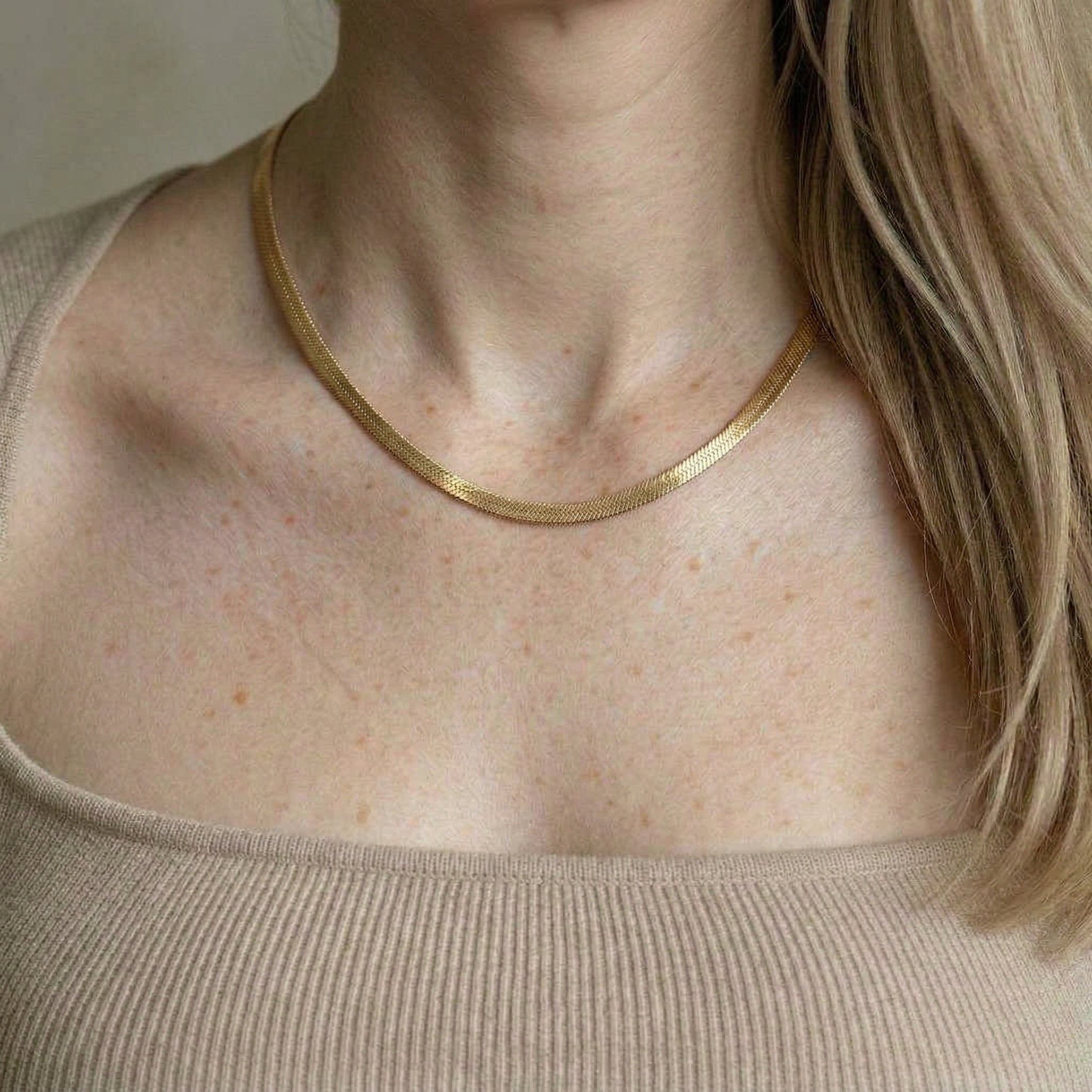 Gold-plated necklace worn on model's bare neck