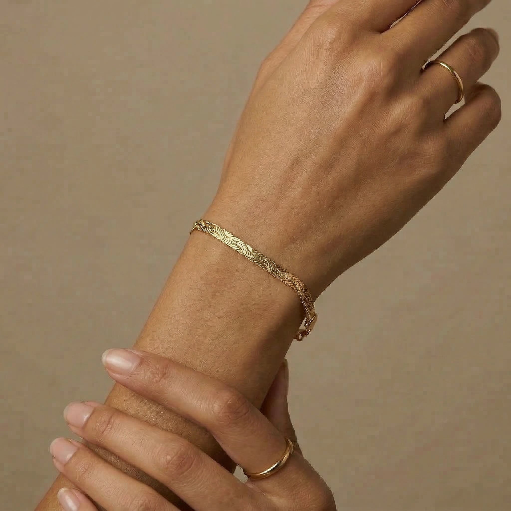 Gold-plated bracelet worn on wrist with rings