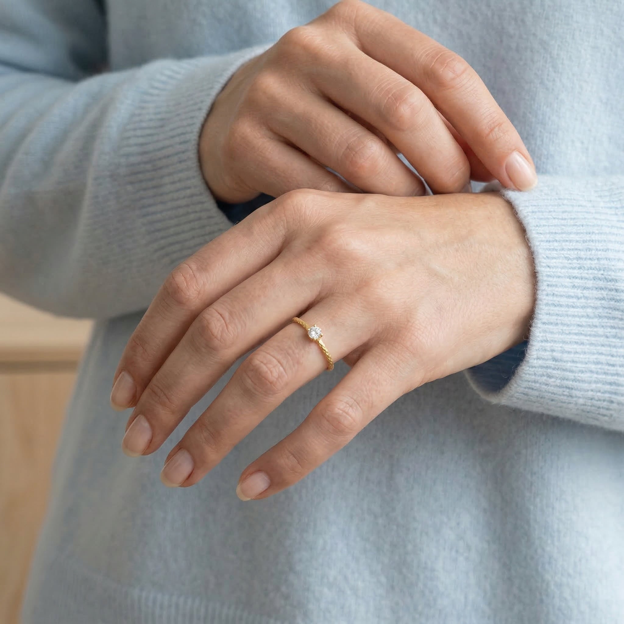 Gold-plated ring worn on hand with sweater