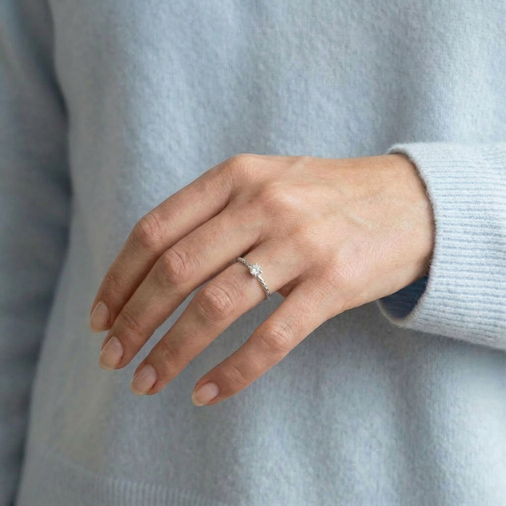 Silver ring worn on hand with light blue sweater