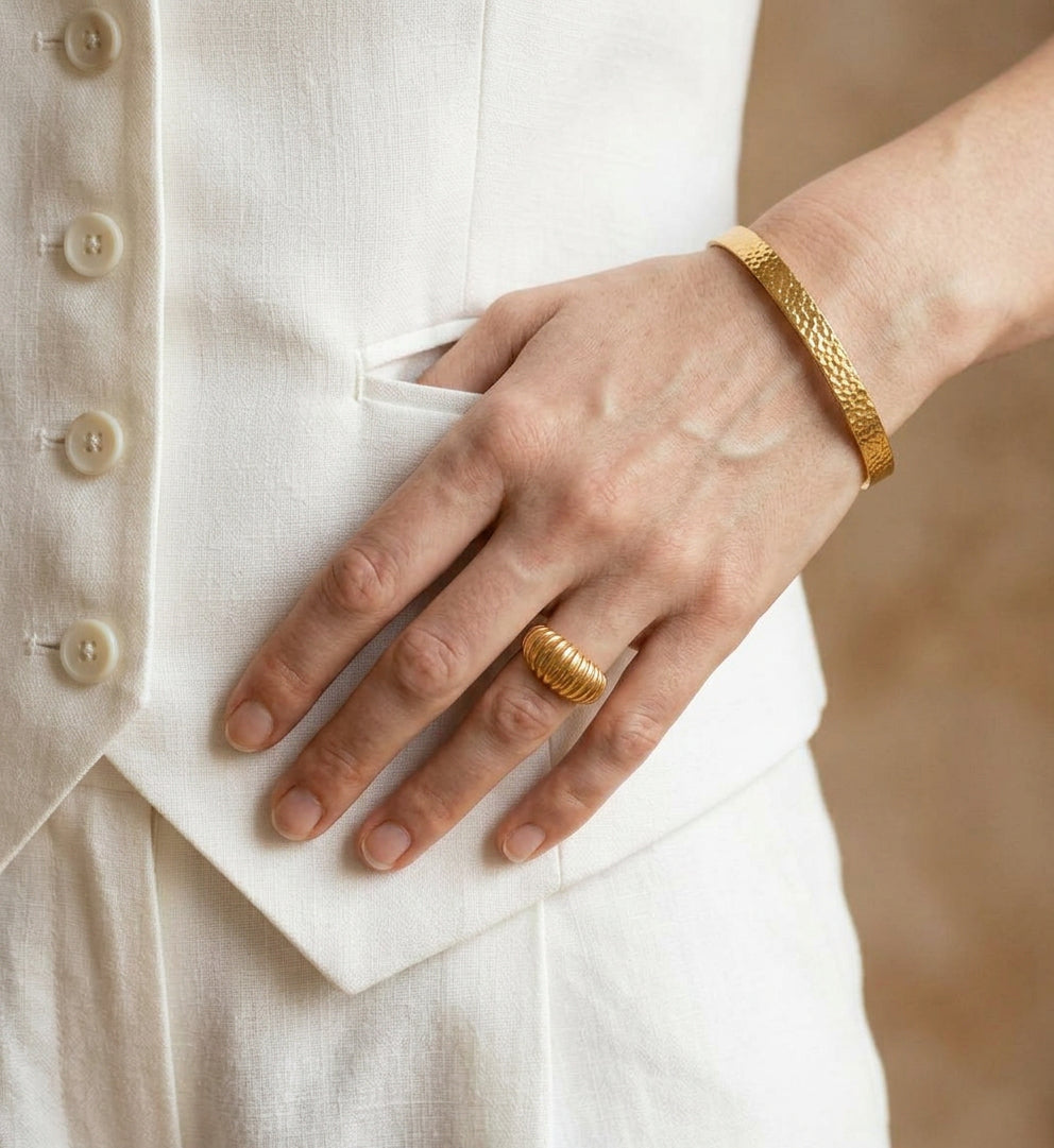 Gold-plated ring worn on hand with white vest