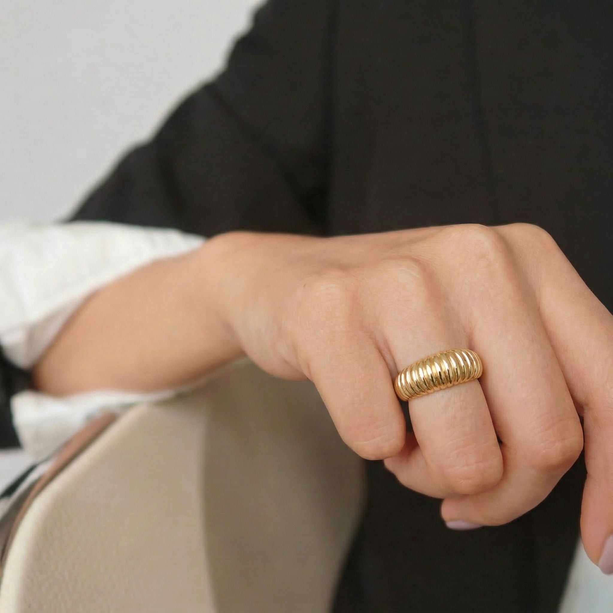 Gold-plated ring on hand with black blazer