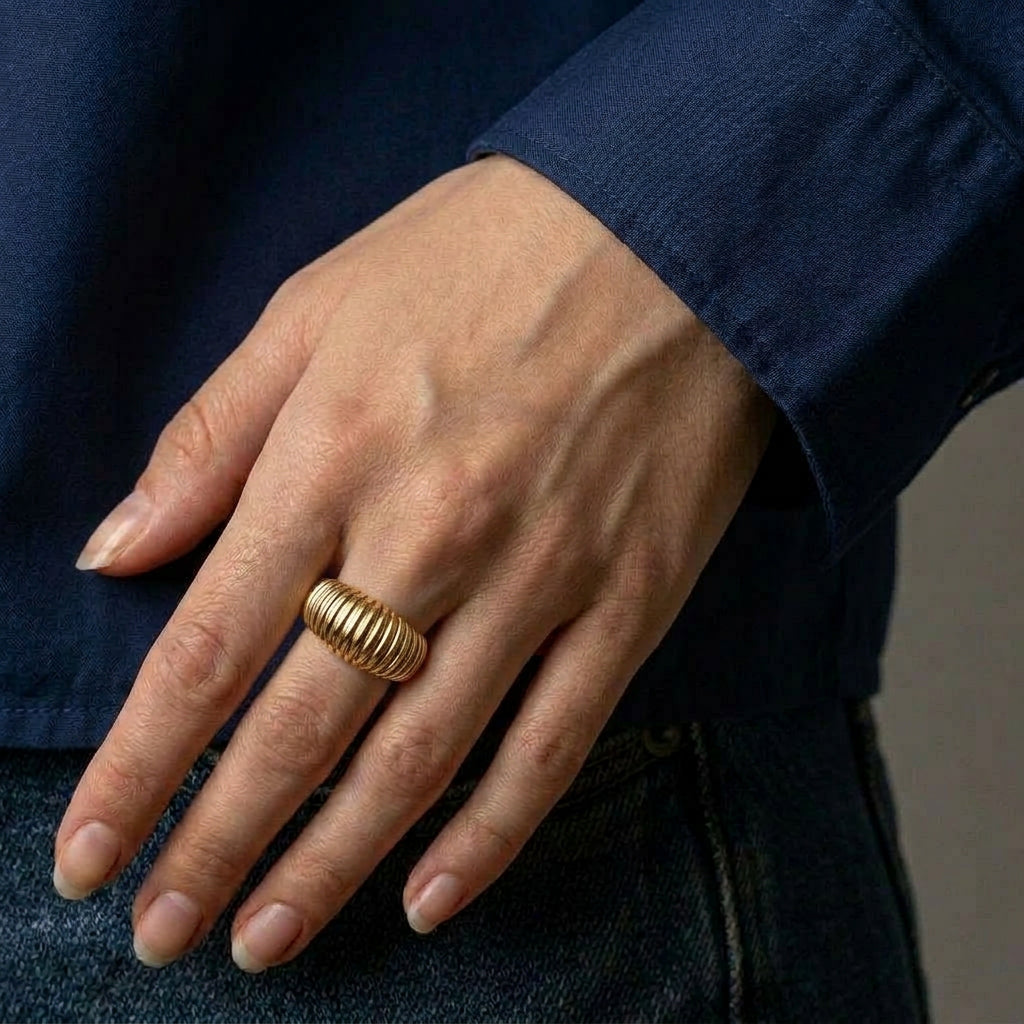 Gold-plated ring on hand with blue shirt