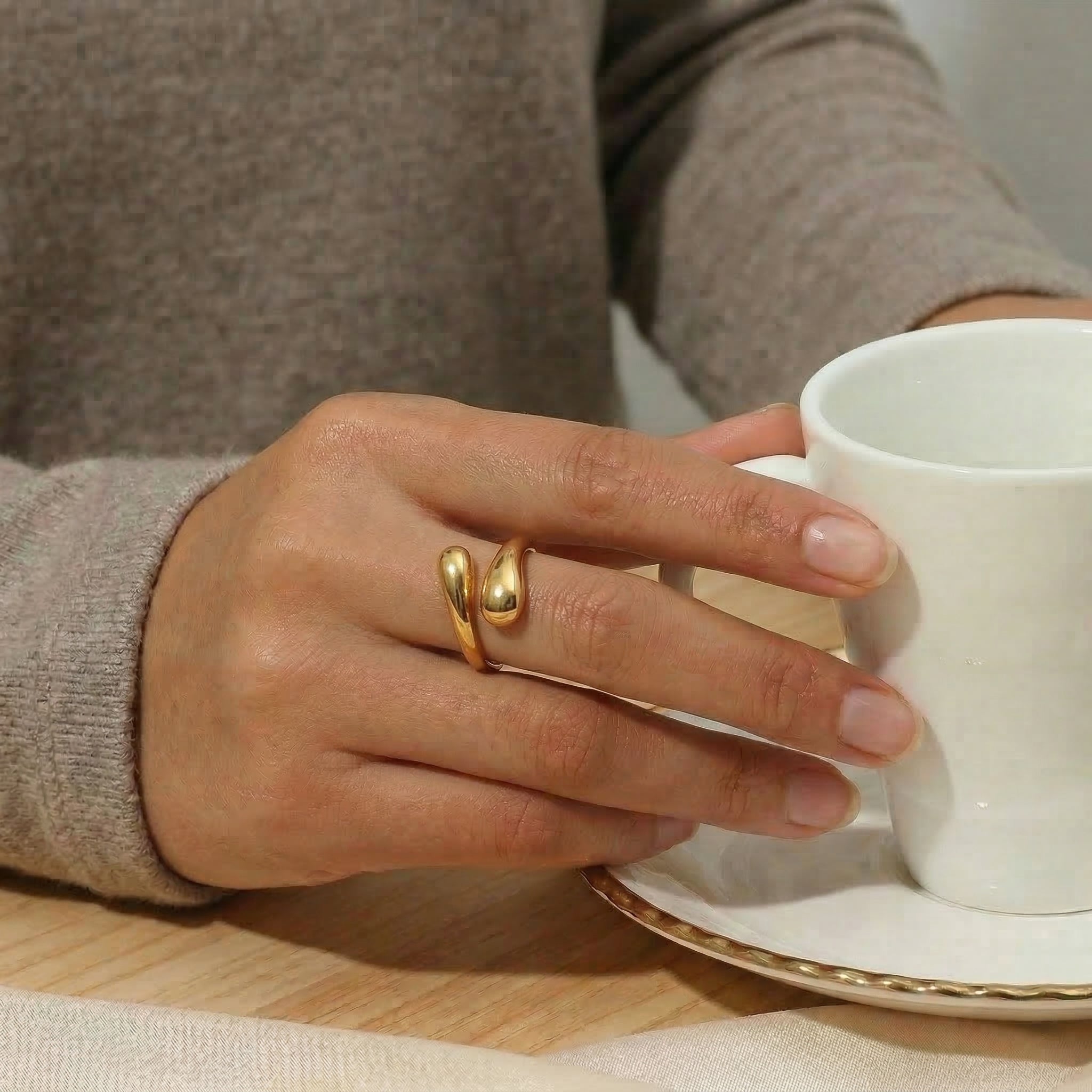 Gold-plated ring worn on hand holding coffee cup