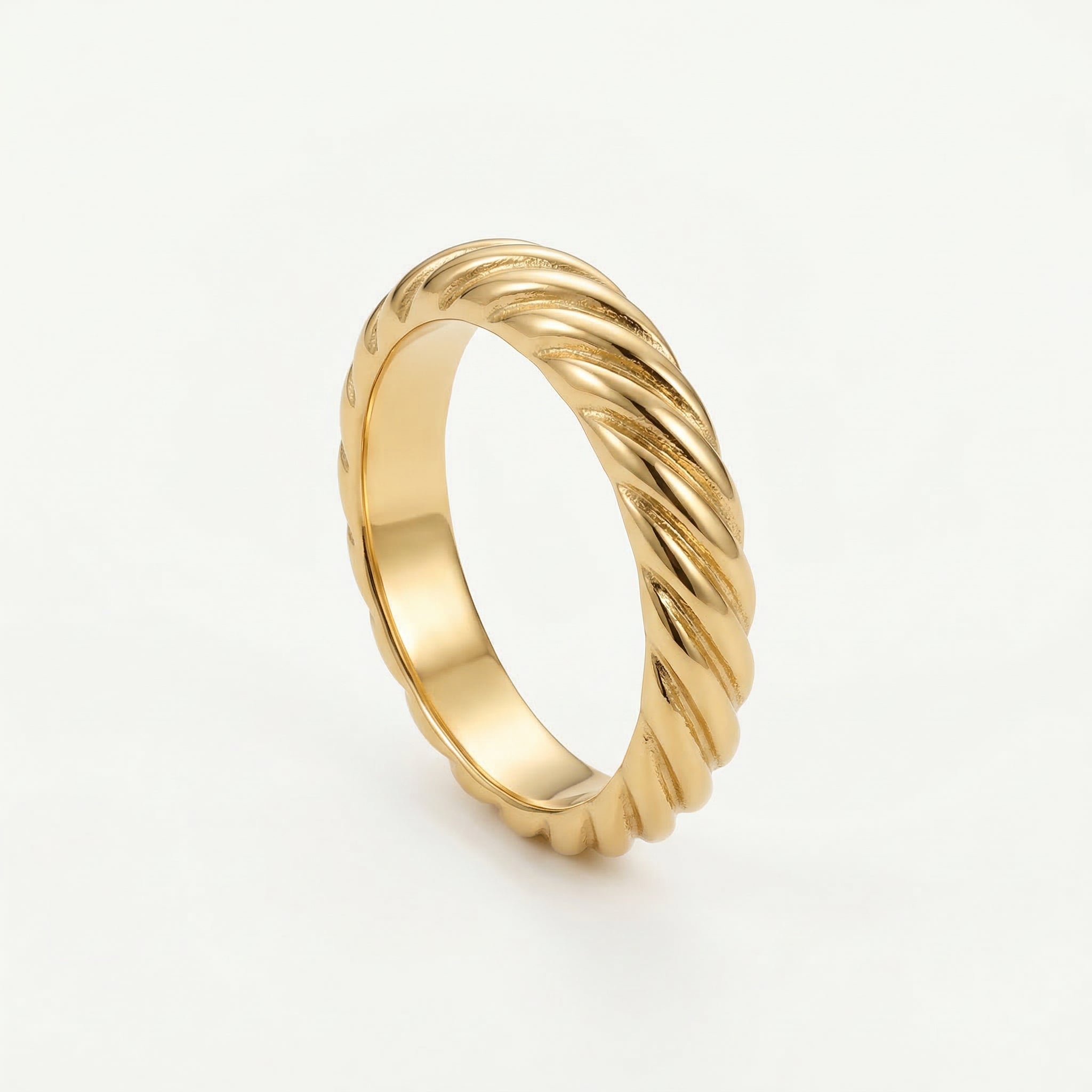 Gold-plated twisted ring on white background