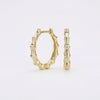 Pair of gold bamboo-shaped hoop earrings on a white background.