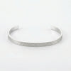 Silver cuff bracelet with a hammered texture on the outer surface, smooth on the inside.