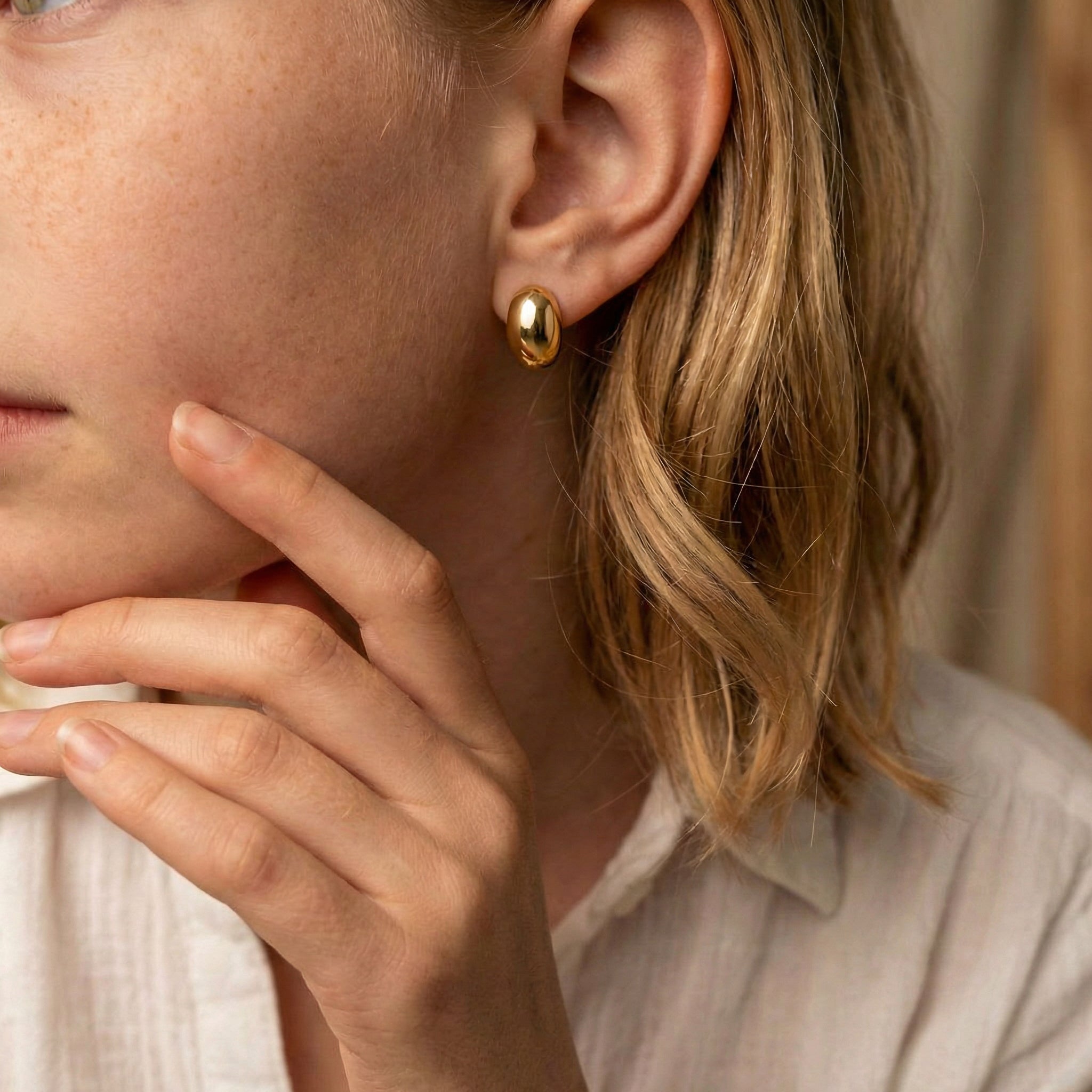 Gold-plated bean stud earring on model's ear