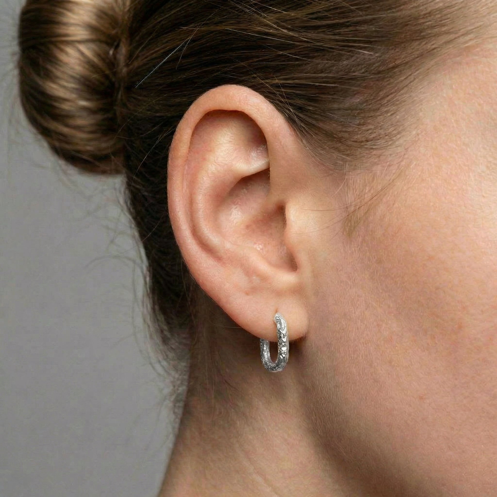 Silver hoop earring worn on ear