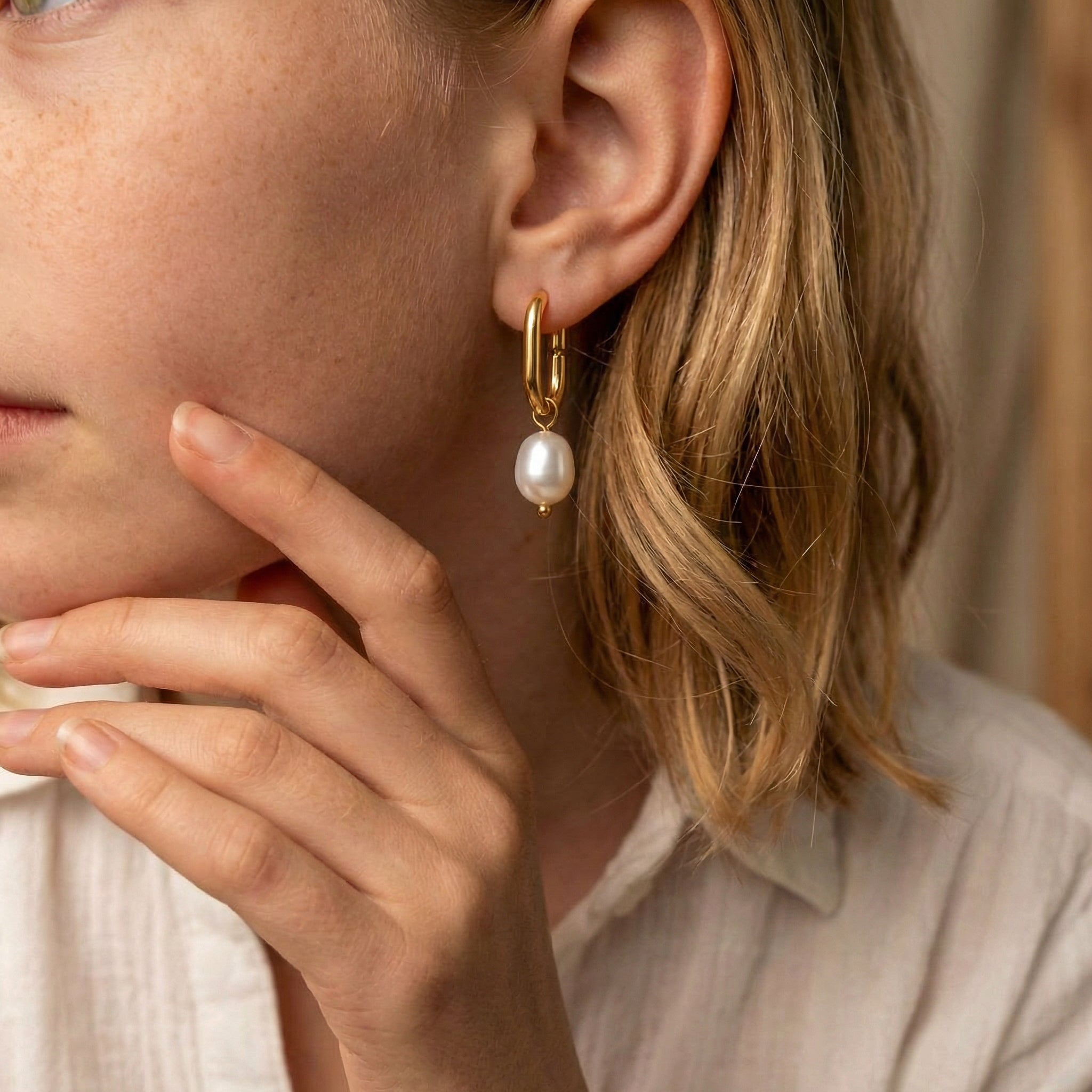 Pearl hoop earrings gold-plated earring worn on model with hand near face