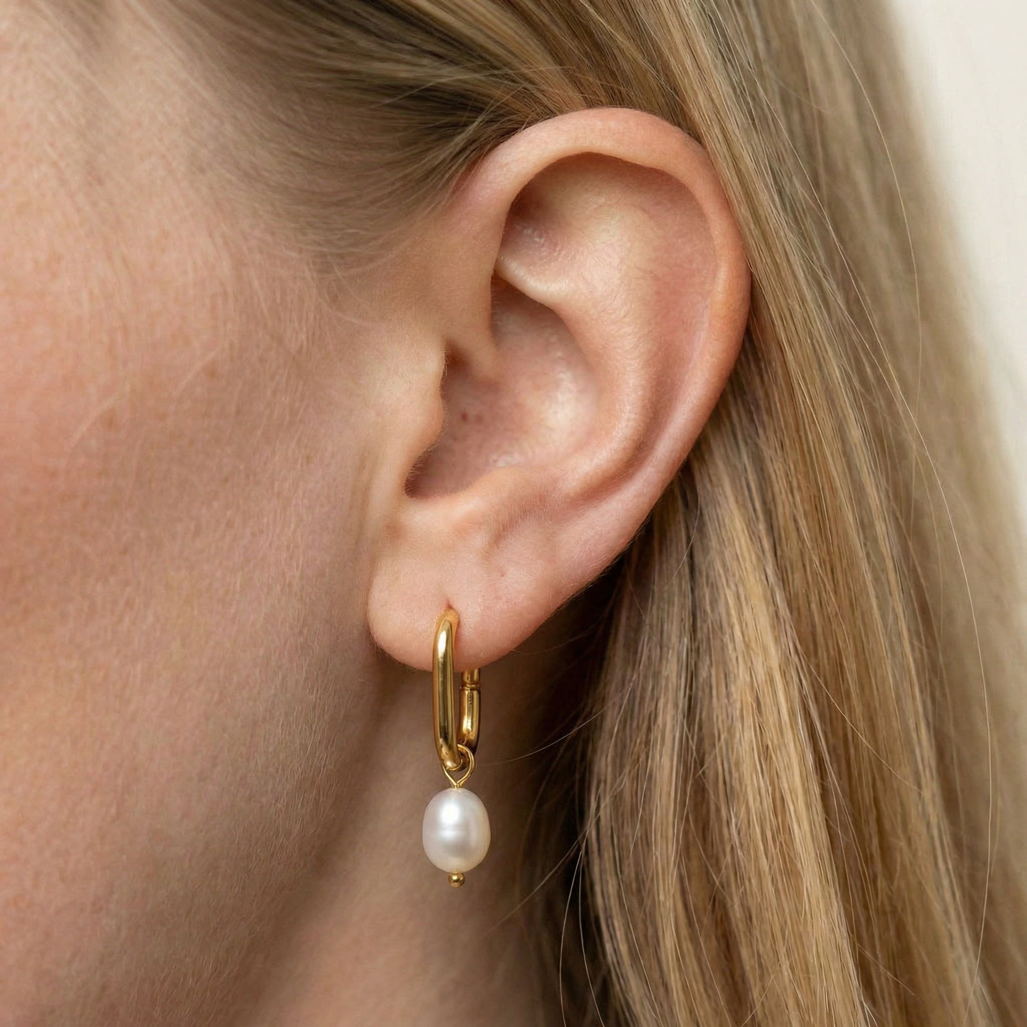 Pearl hoop earrings gold-plated earring worn on model's ear, close-up