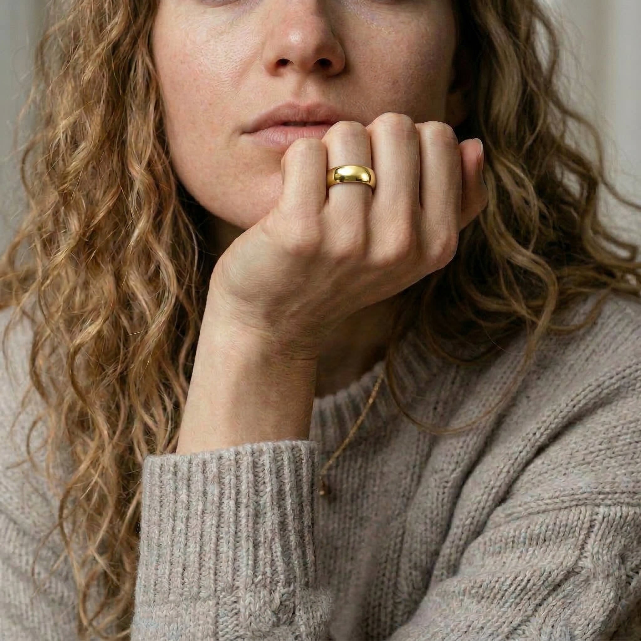 Gold-plated ring worn on hand, model's face