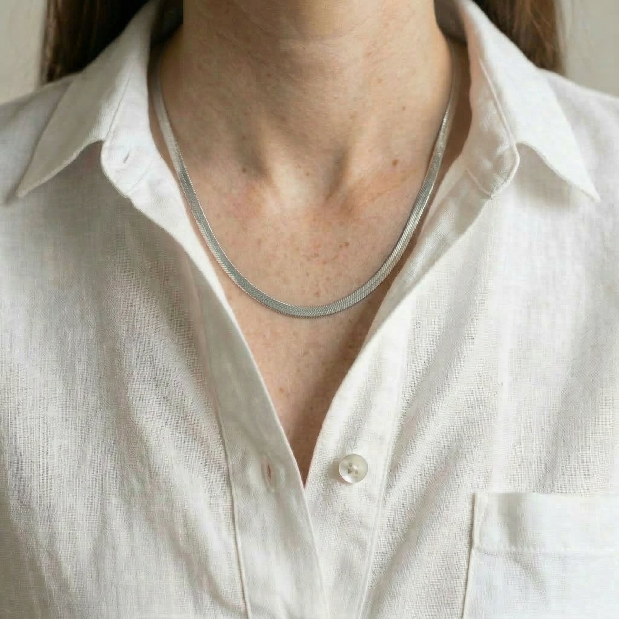 Silver necklace on model wearing white shirt