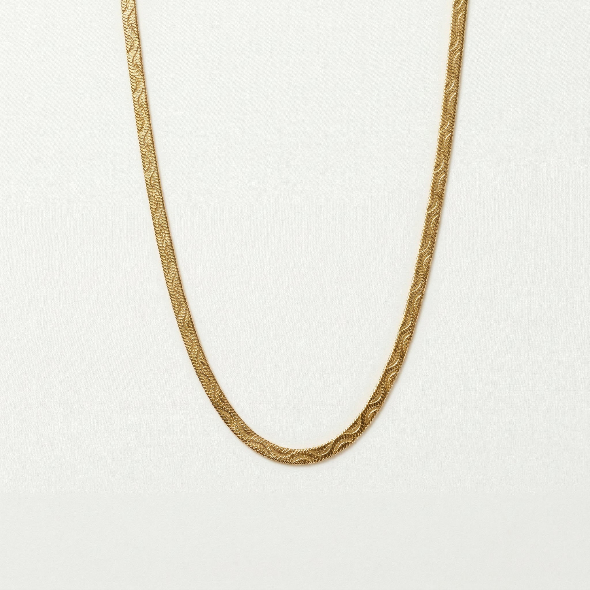 Gold-plated wave necklace on white background