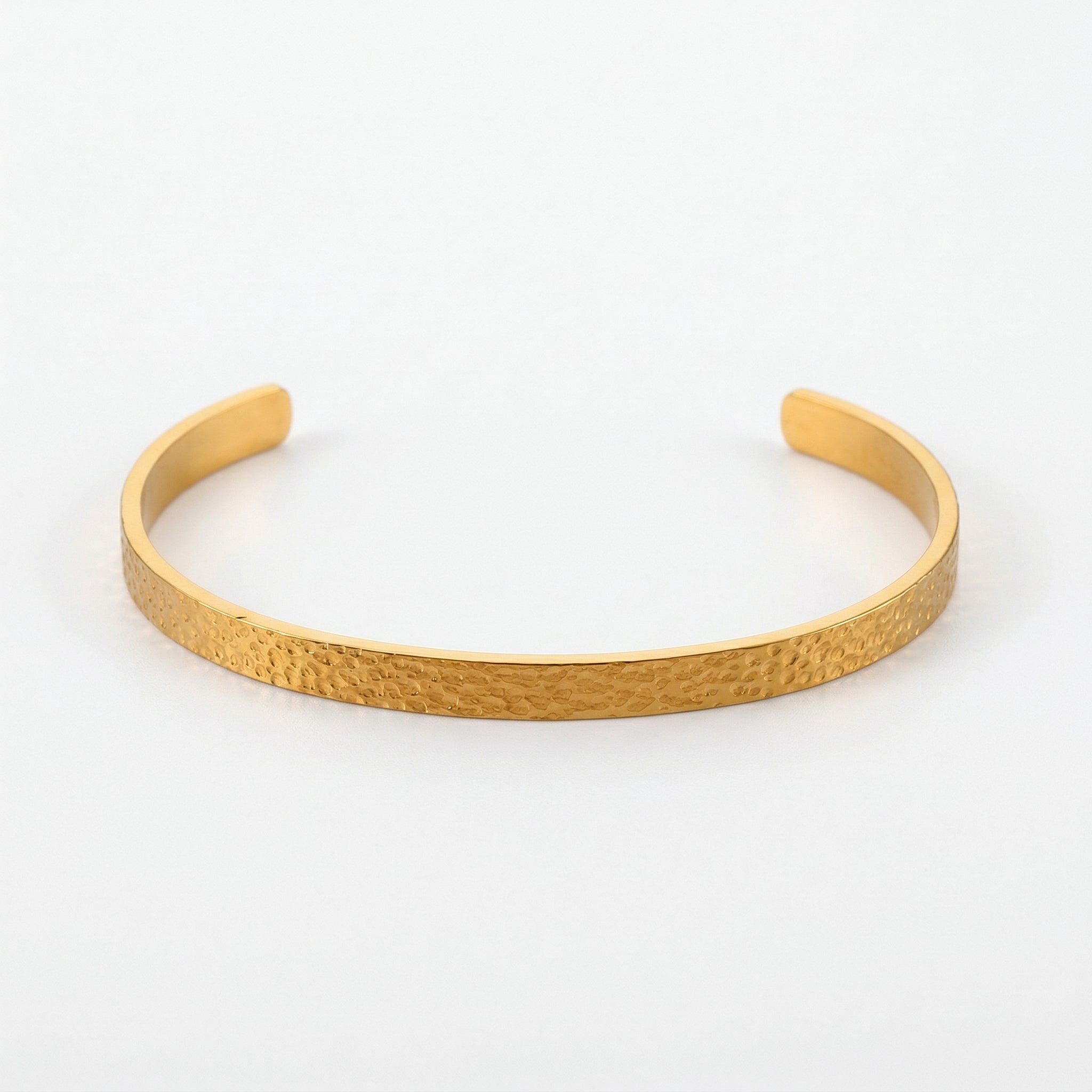 Gold-plated hammered bangle on white background