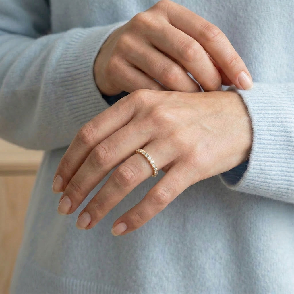 Gold-plated ring worn on hand with light blue sweater