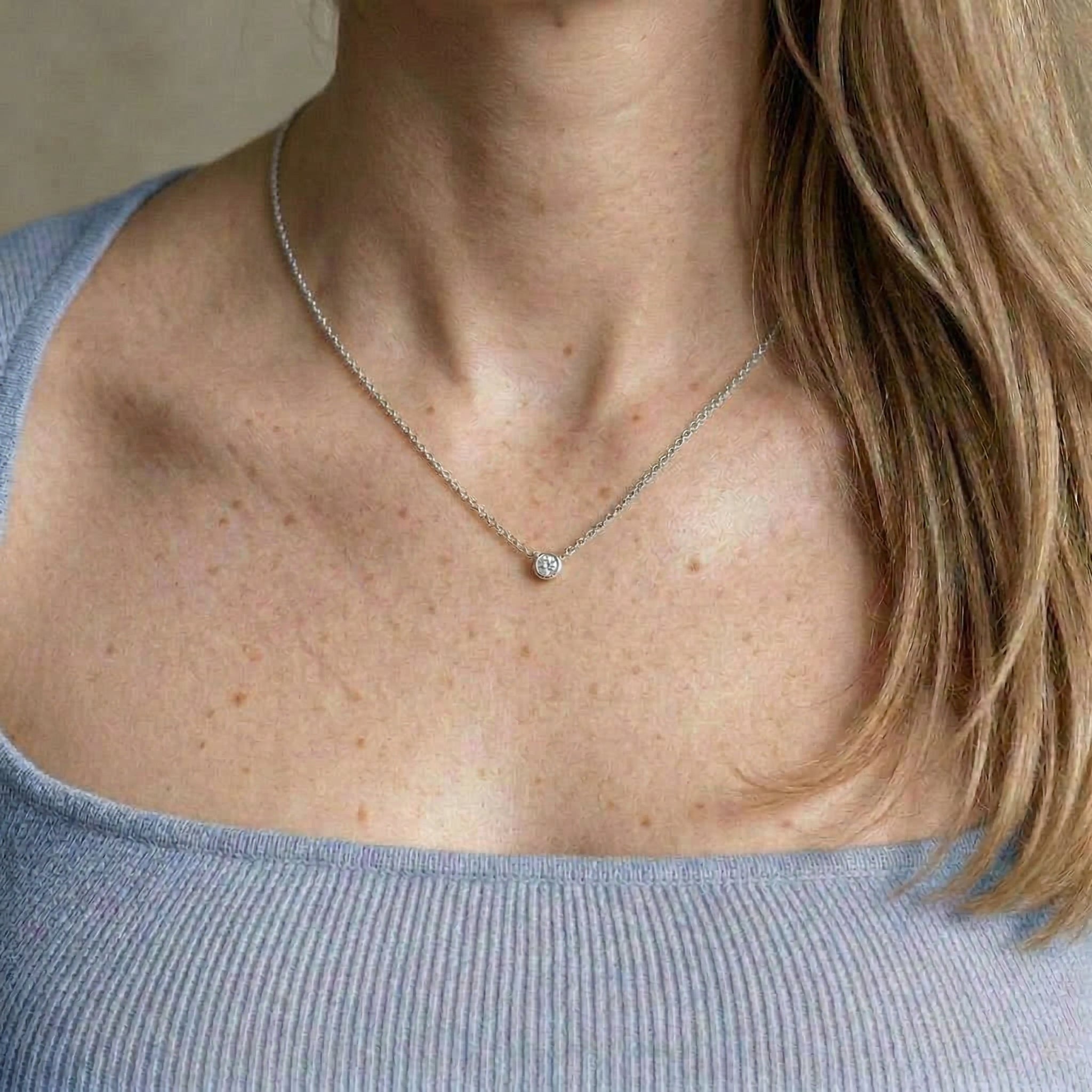 Silver necklace worn on model with blue top