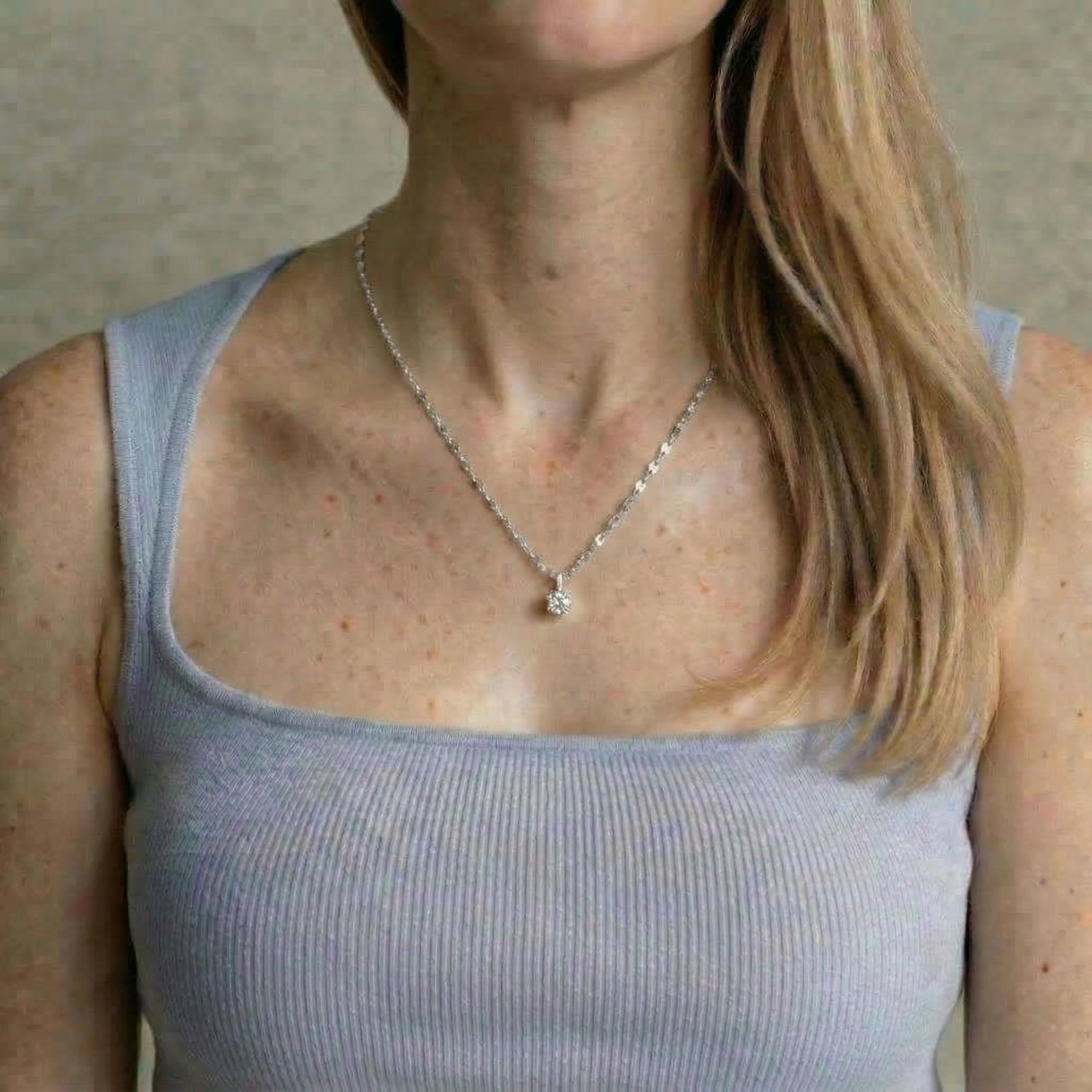 Silver necklace worn on model with gray top